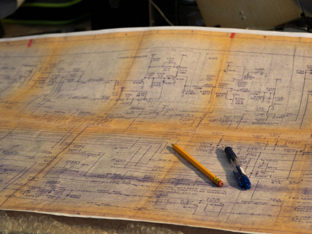 A close-up of a detailed engineering blueprint featuring a pen and pencil placed on a desk.